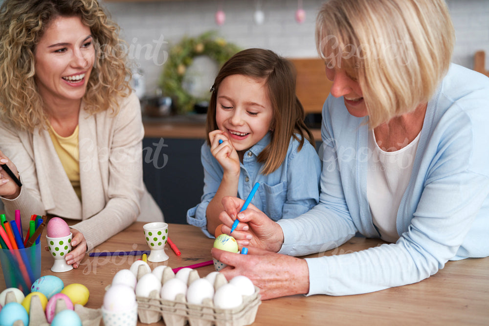 Three generations of women decorate easter eggs