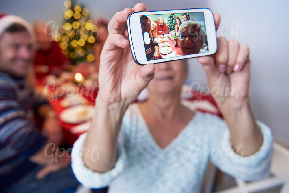 Modern grandmother taking a photo of the family