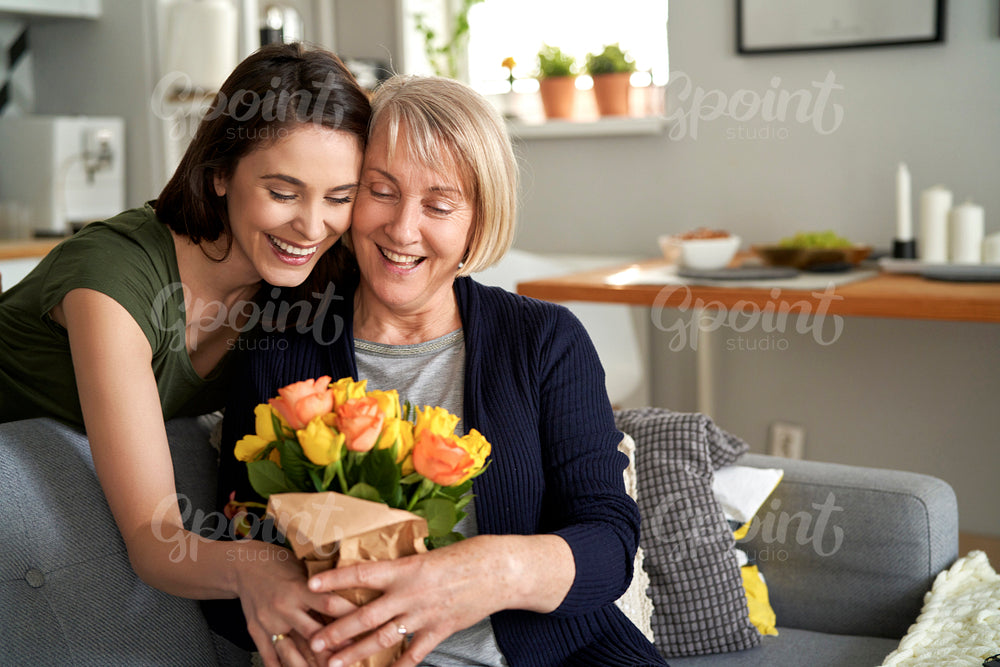 Happy daughter giving flowers to her mother