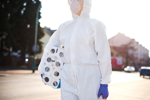 Unrecognizable person in protective suit walking with some shopping
