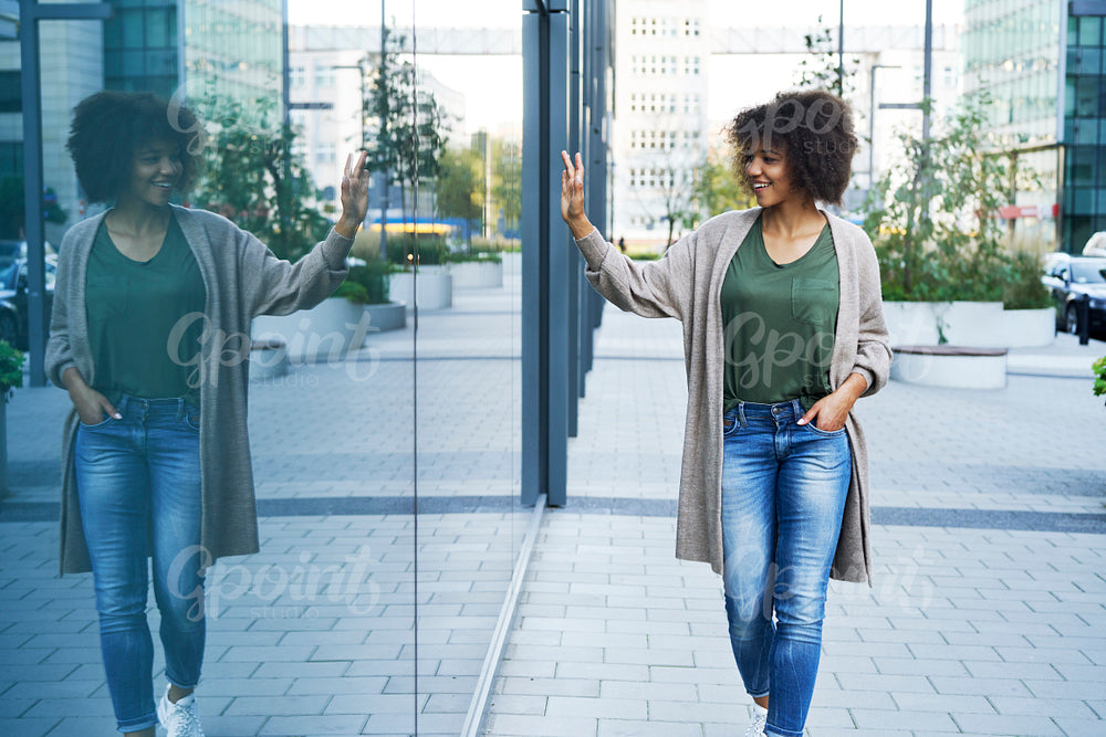 Woman walking outdoors and waving someone through the glass