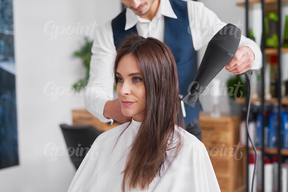 Male hairdresser using hair dryer