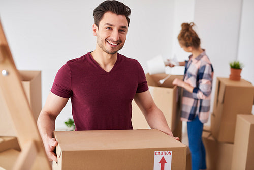 Smiling man moving into new home and unpacking his stuff