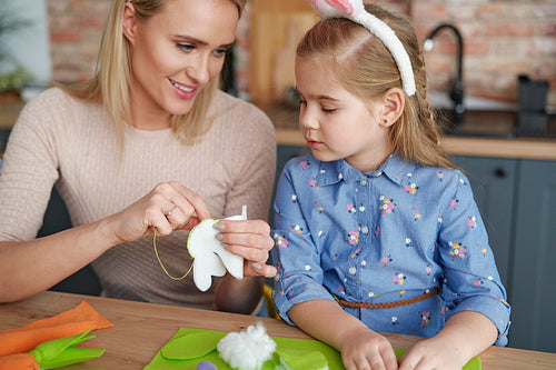 Mother teaches her little daughter sewing Easter decorations