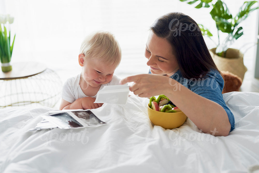 Woman and her little son browsing pregnant photographies