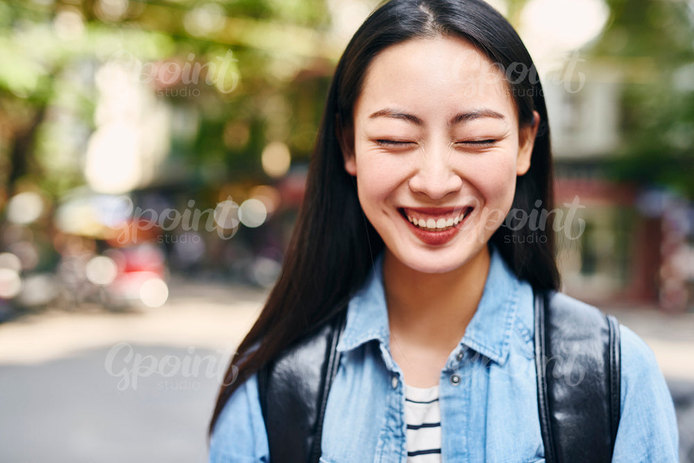 Portrait of young joyful woman with backpack in the city