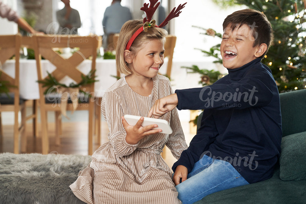 Two caucasian children holding mobile phone and having fun 