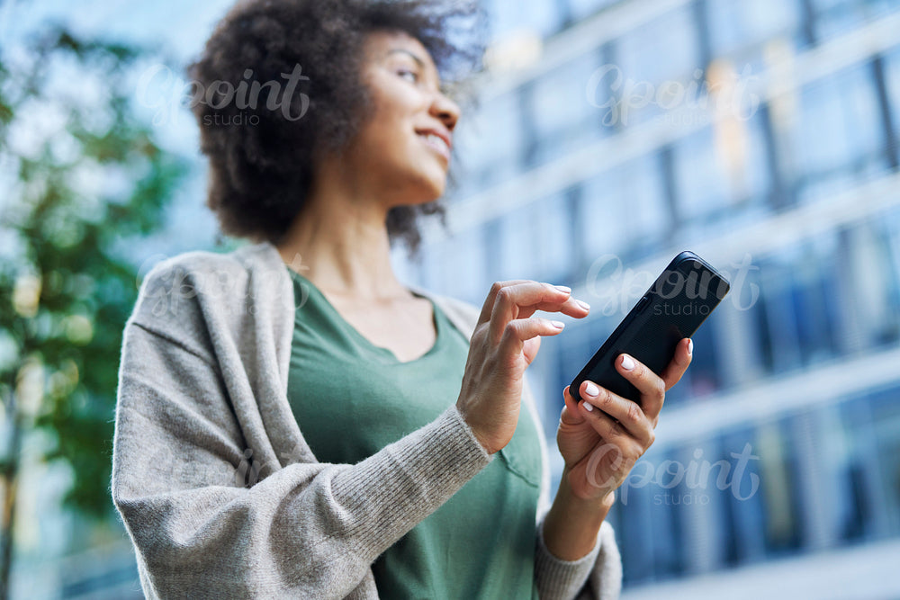 Low angle view of afro woman with mobile phone