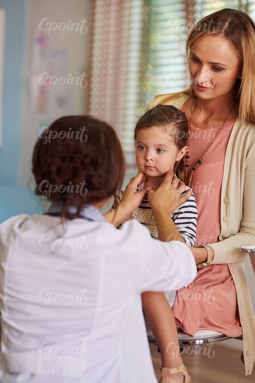 Female doctor checking the little girl's throat
