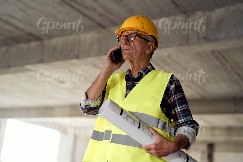 Senior caucasian man holding plans on the construction site 