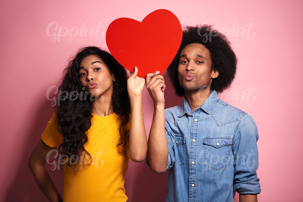 African couple with red heart in studio shot.