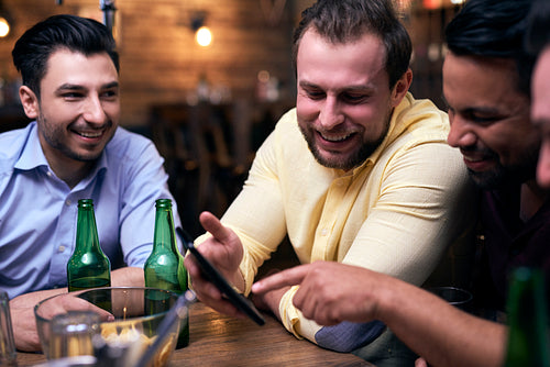 Men using mobile phone during meeting in the pub