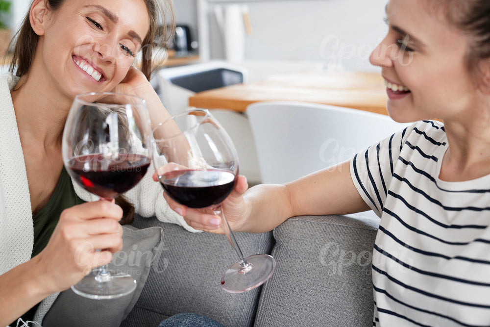 Smiling friends sitting with glass of wine