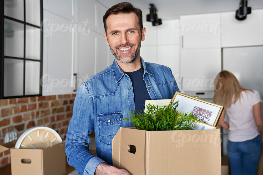 Portrait of smiling man holding cardboard box during moving house
