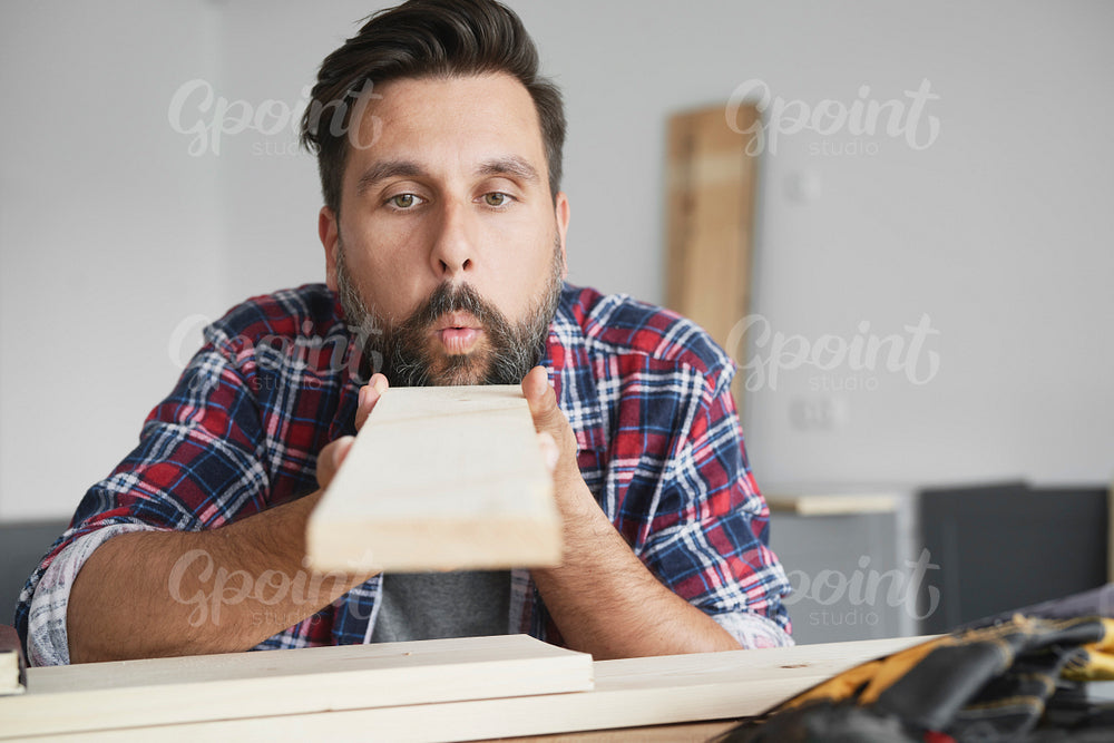 Carpenter blowing dust off a board
