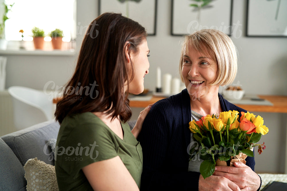 Woman giving mother bouquet of flowers