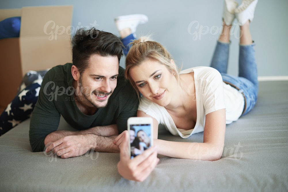 Couple taking picture in their own new bedroom