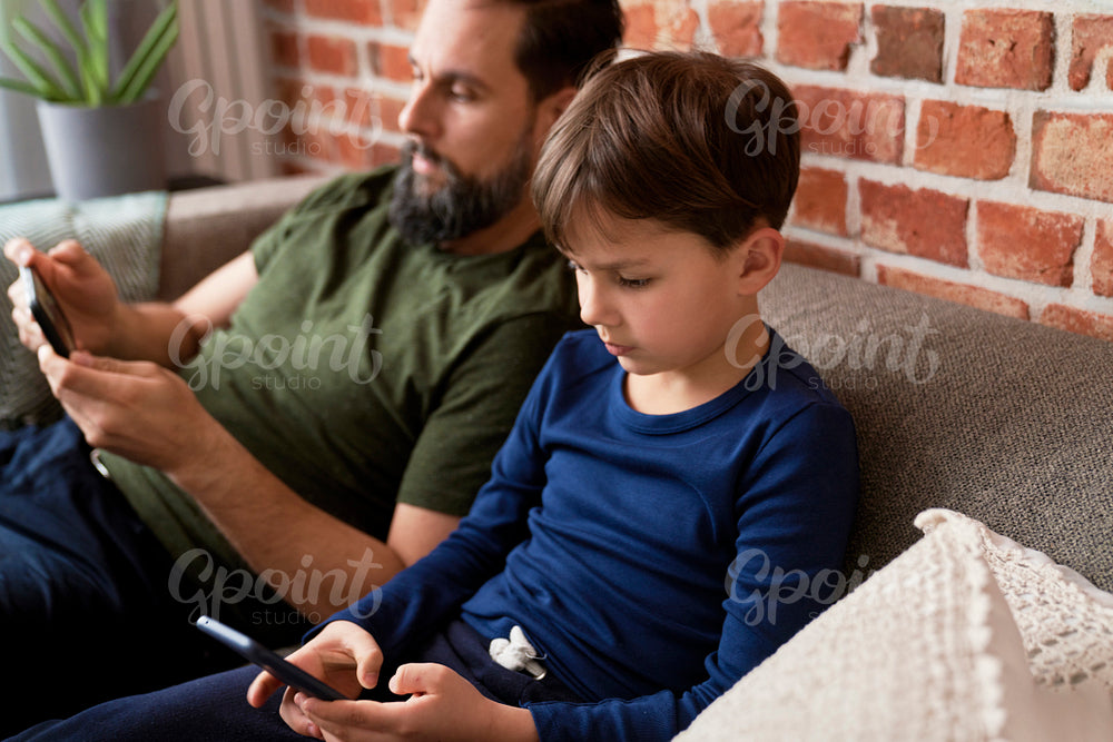 Close up of father and son using mobile phone