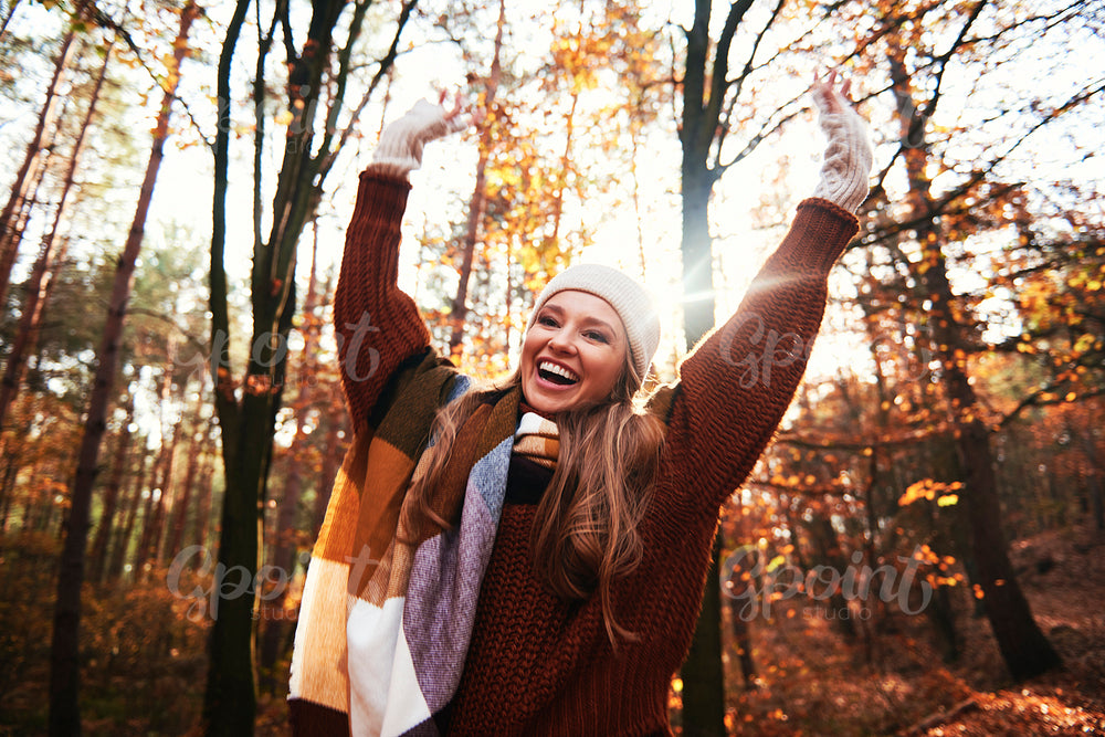 Happy beautiful woman with hands up in autumnal forest