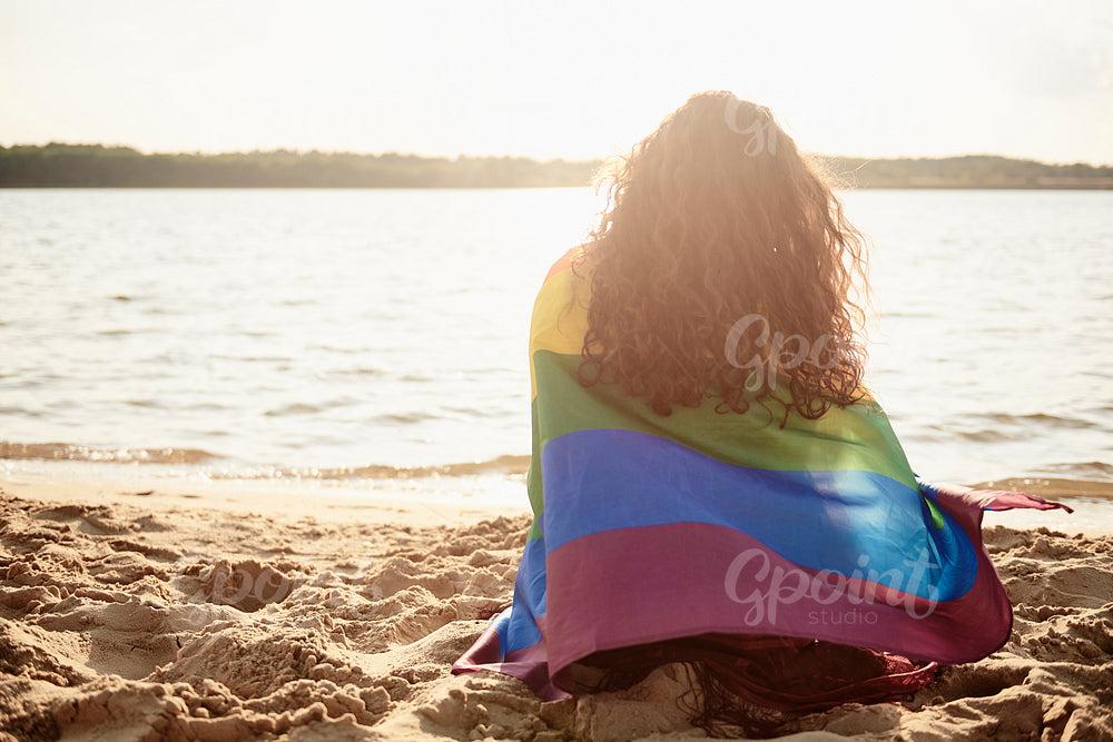 Rear view of young woman covered with rainbow flag