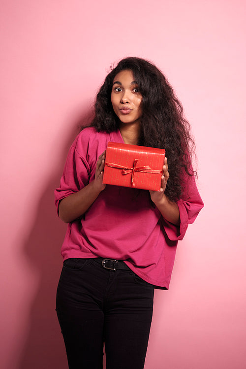 Young African woman holding red present in studio shot.