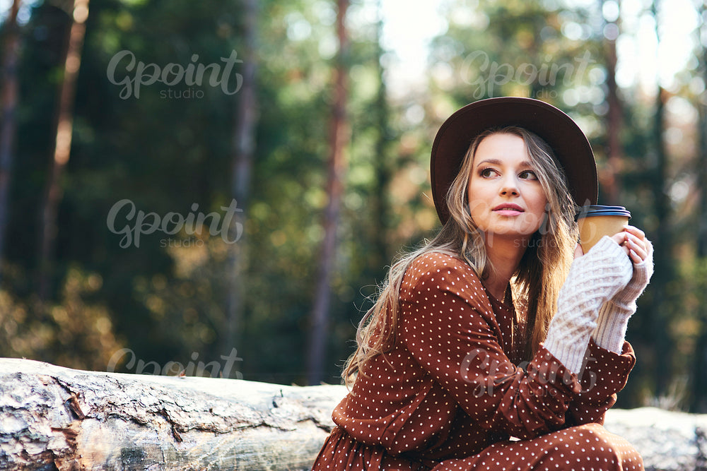 Beautiful woman drinking hot coffee in autumn forest