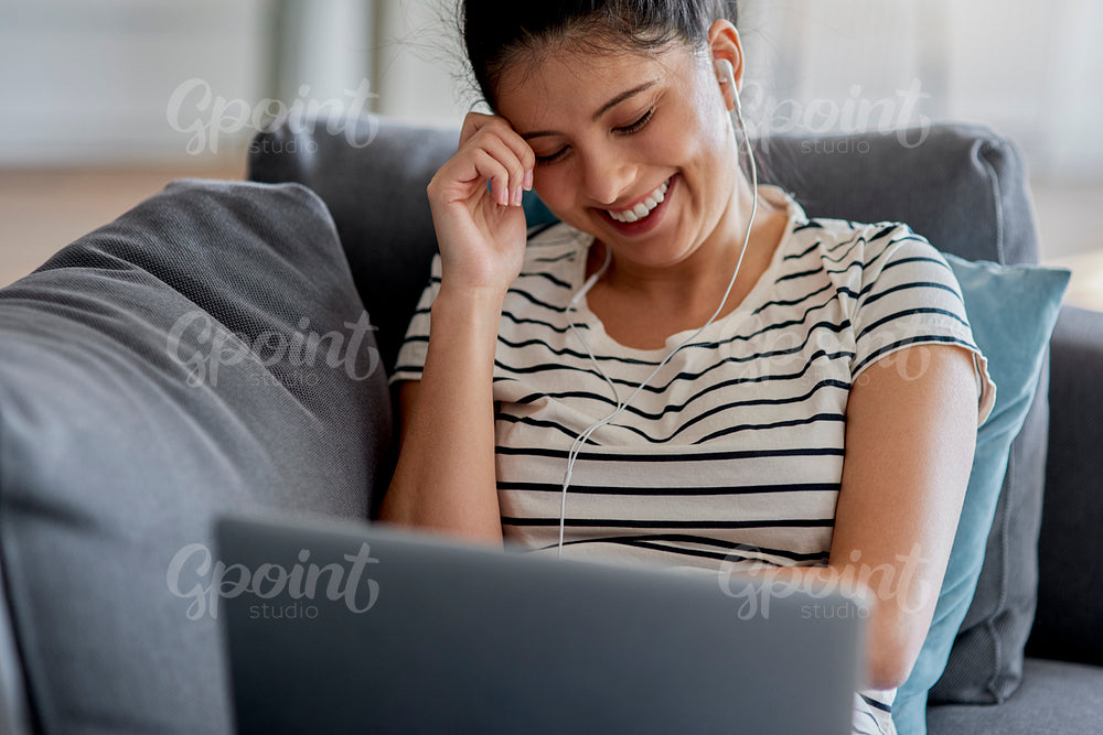 Young Asian woman is watching something funny on a laptop.