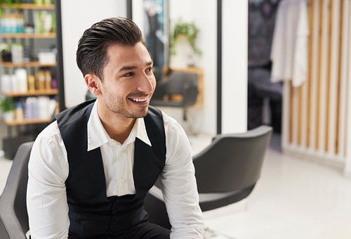 Portrait of smiling hairdresser sitting in hair salon