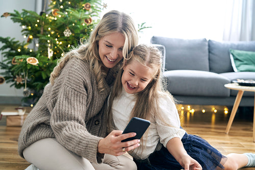 Caucasian mother and daughter having fun while browsing smart phone in the living room