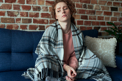 Depressed young caucasian woman flooring in silence  next to sofa
