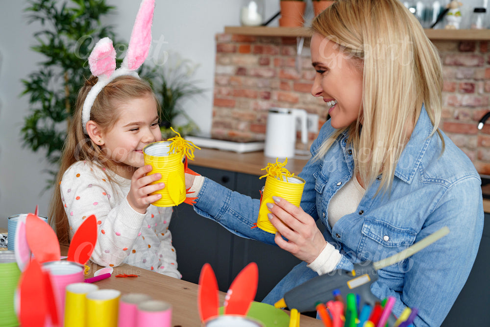 Happy mom and daughter playing with handmade Easter chickens