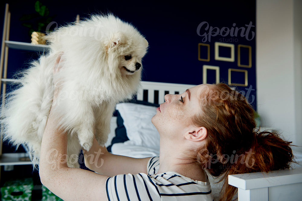 Woman giving kisses to her fluffy pet dog