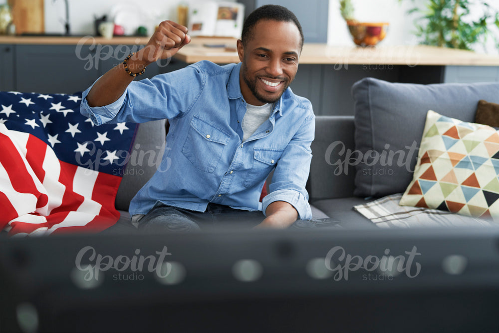 Black man cheering in front of TV