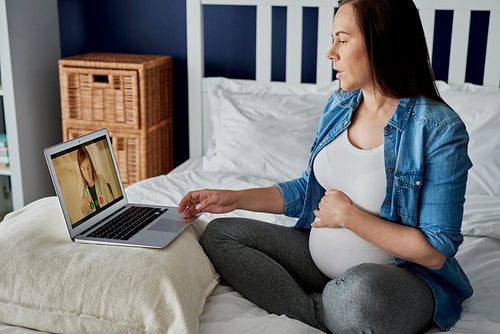 Pregnant woman having a video call with a doctor