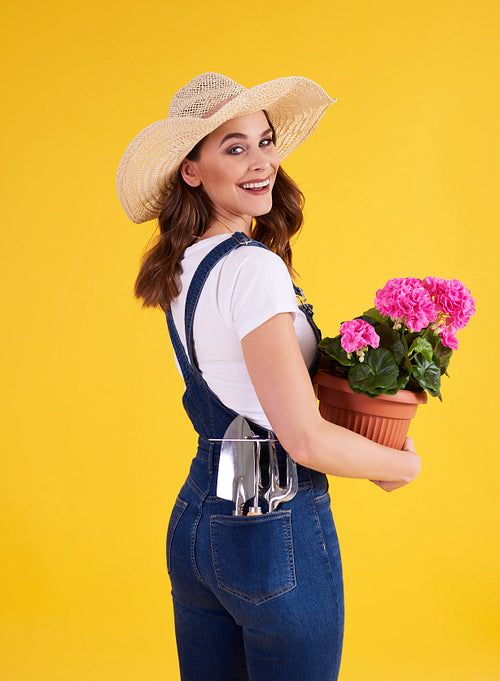 Smiling woman holding flower pot with beautiful flowers