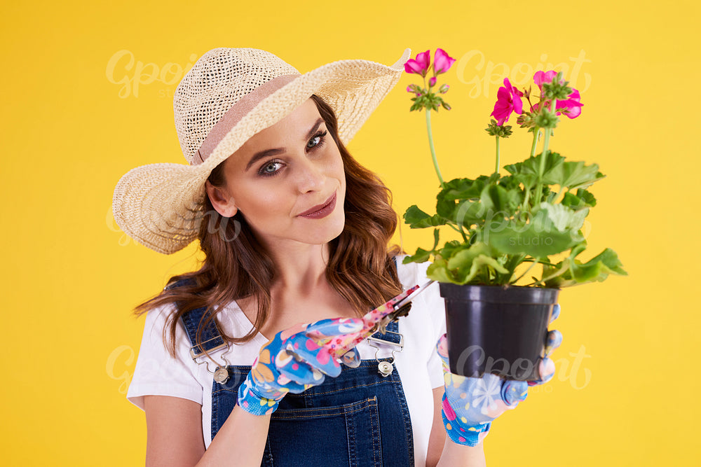 Smiling woman pruning flower in flower pot