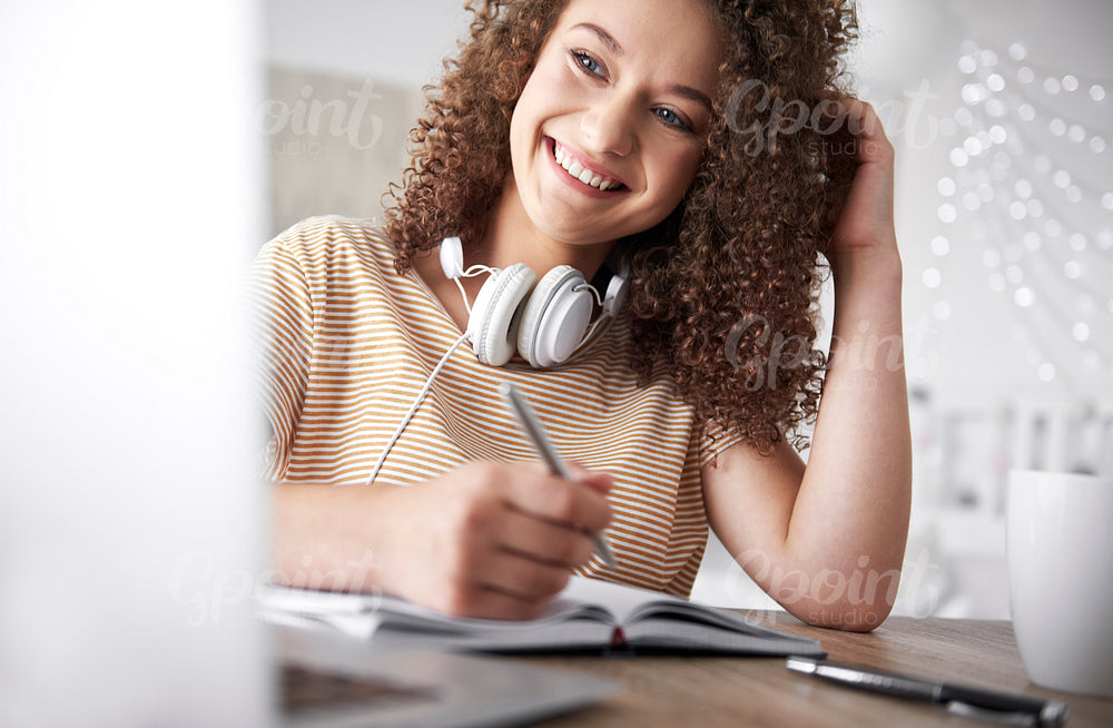 Smiling teenage girl studying at home