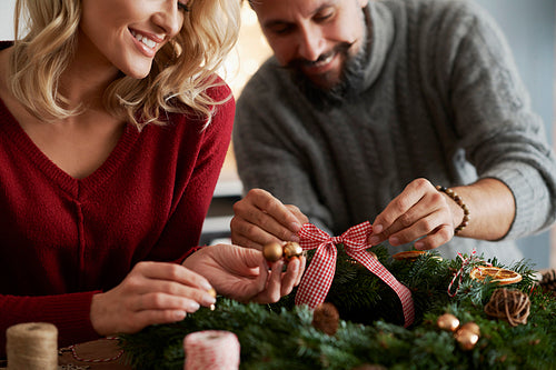 Close up of couple decorating Christmas wreath