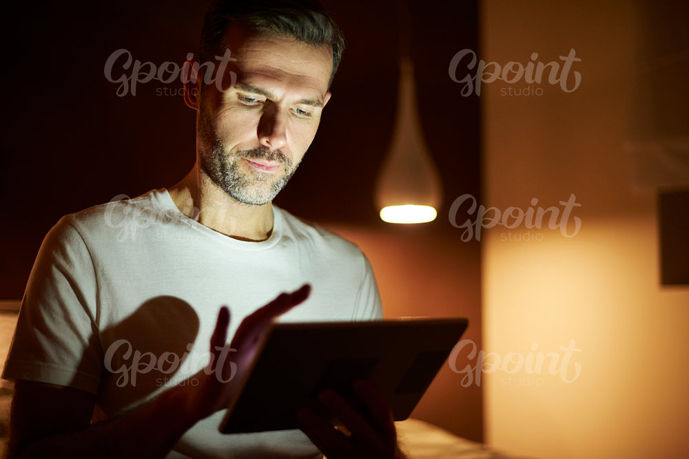 Focused man using tablet at night
