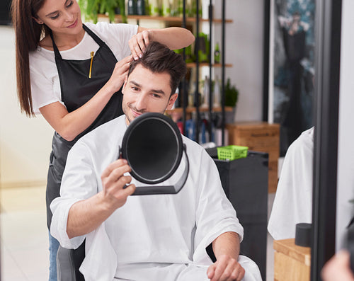 Female hairdresser creating fashionable hairstyle her male customer