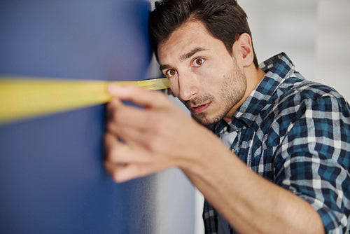 Precise man using a measure tape on wall