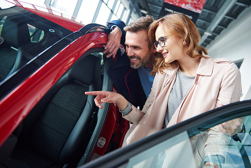 Adult couple admiring car in the showroom