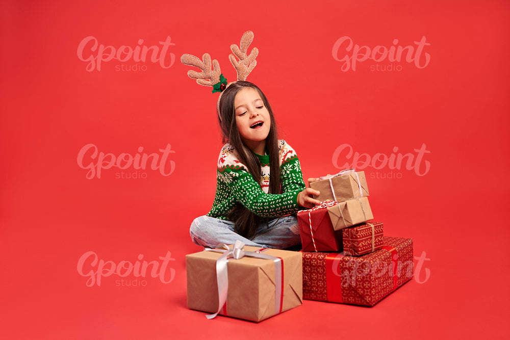 Girl and a stack of Christmas gifts on red background