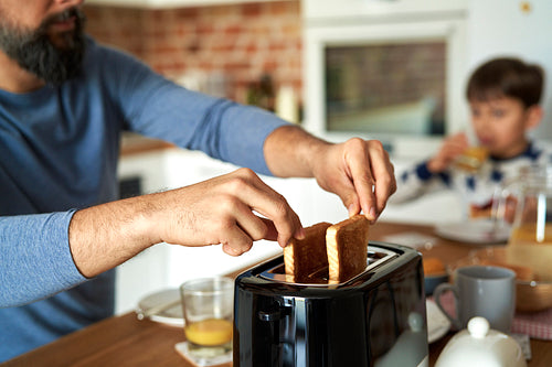 Close up of man pulling toast from a toaster