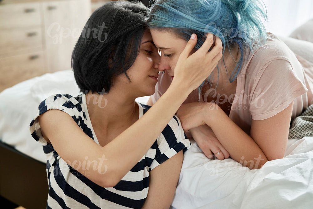 Romantic lesbian couple kissing lovingly in the bedroom