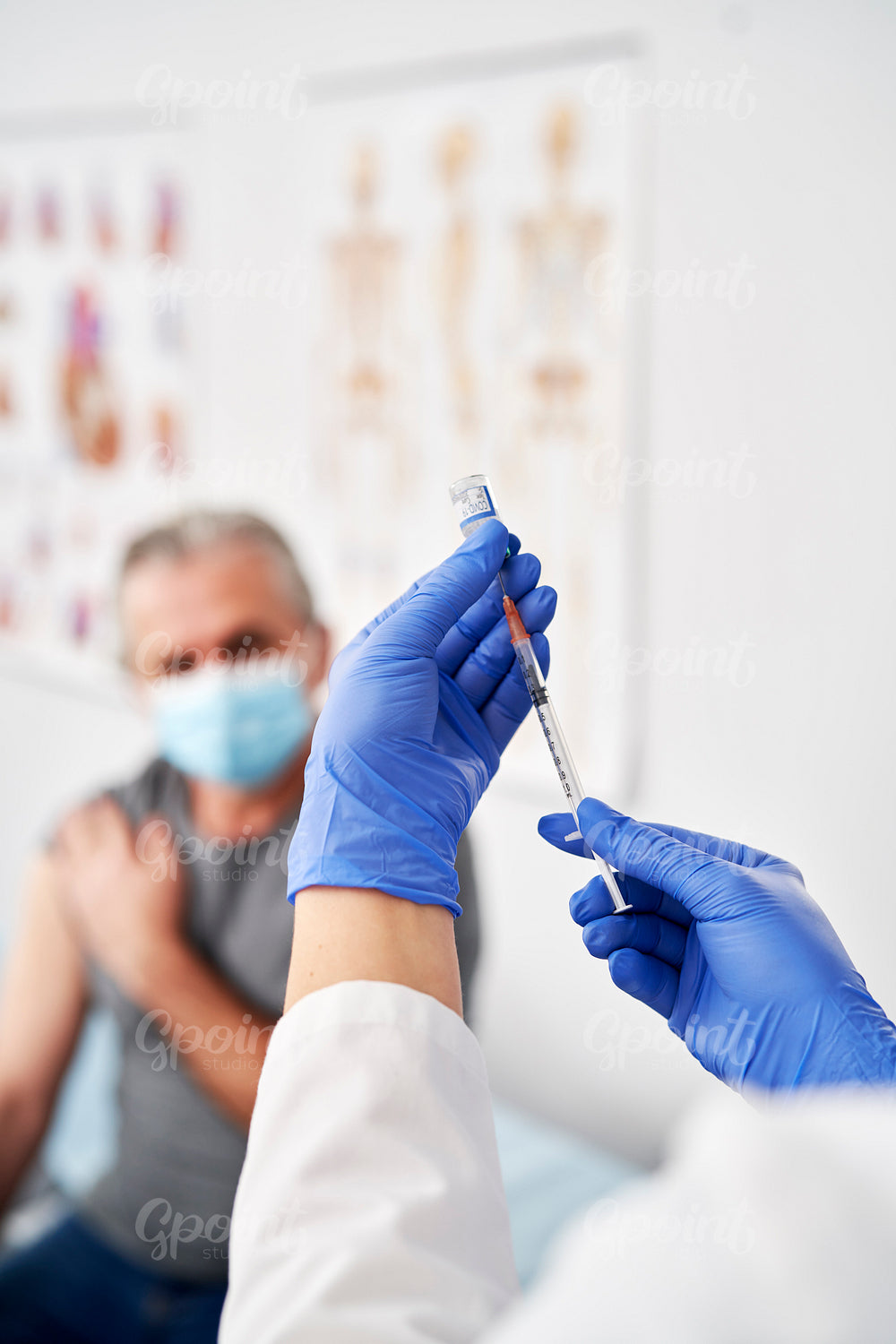 Vertical image of doctor preparing syringe for senior patient