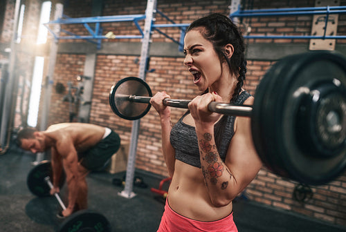 Fit couple lifting barbells in the gym
