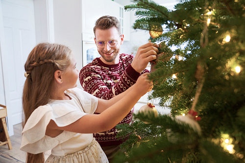Father and daughter decorating the Christmas tree