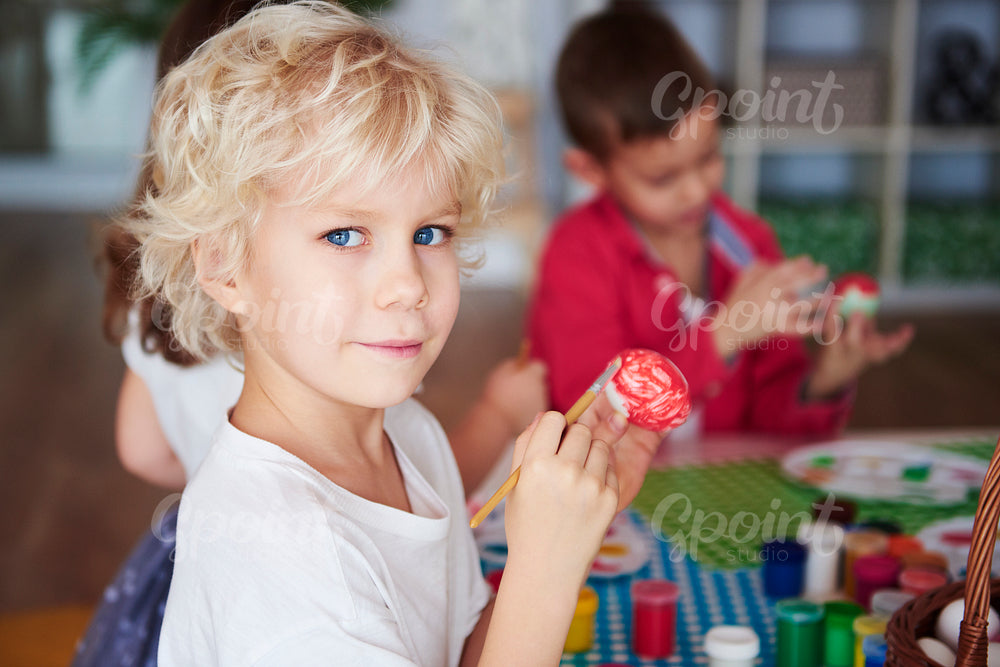 Portrait of smiling boy painting easter eggs
