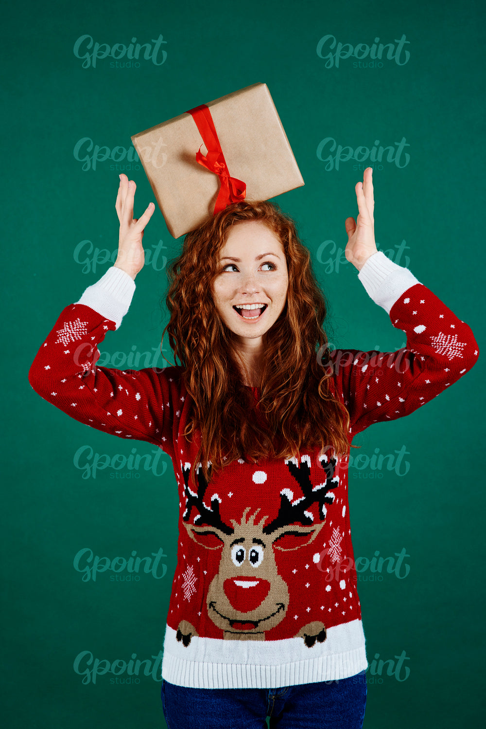 Playful girl with christmas present looking at copy space